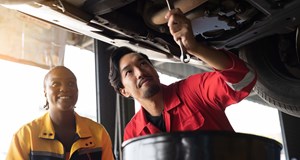 Professional mechanics check, repair and maintenance underneath lifted car at auto car repair service.