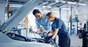 An instructor with a tablet computer is giving a task for a future mechanic. 