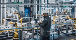 Car factory engineer working on laptop computer in an automotive industrial manufacturing facility