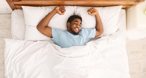 Person happy and lying in bed after a good sleep. Using tips to improve sleep. Longer, restful and deeper sleep. 