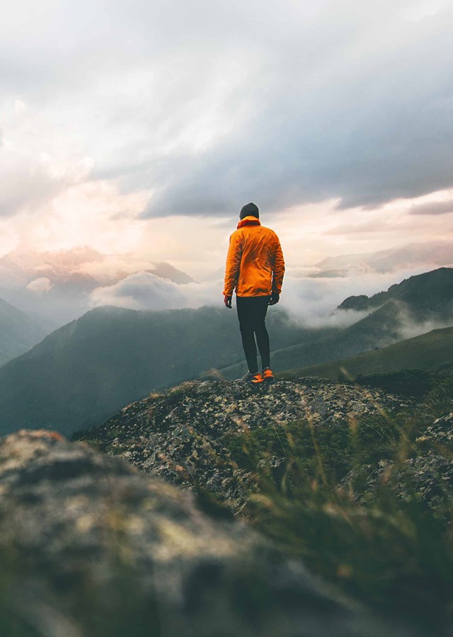 Person standing on top of a fell looking at what they have achieved