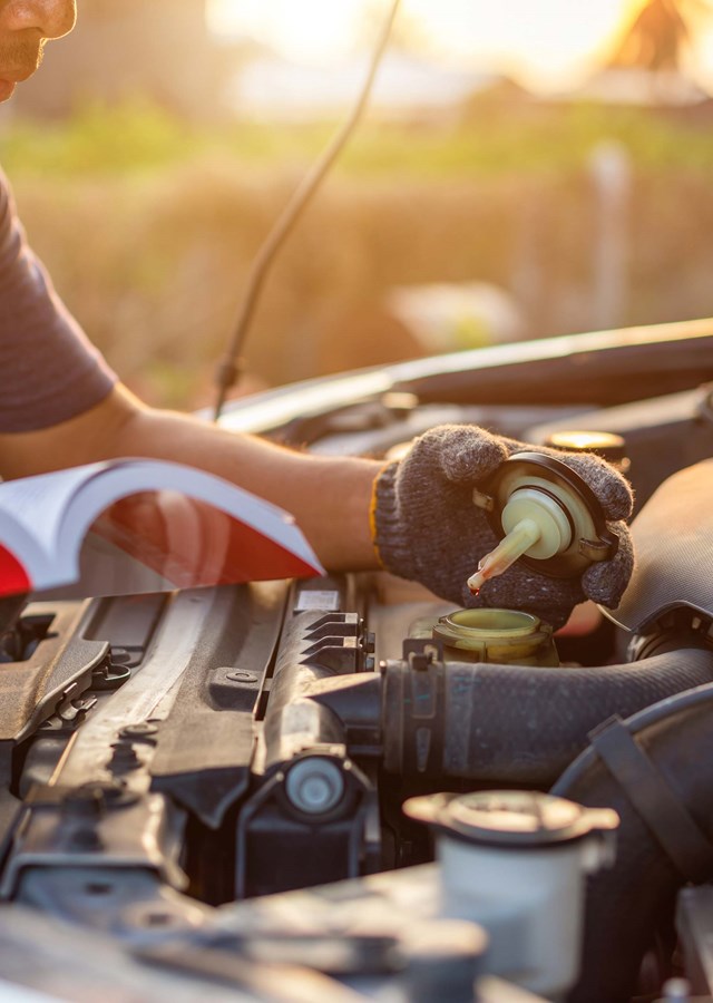 Man reviewing service manual whilst testing coolant